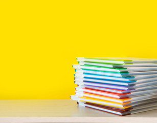 Stack of colorful books on color background.