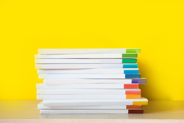 Stack of colorful books on color background.