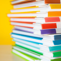 Stack of colorful books on color background.