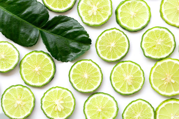 Fresh slices of bergamot fruits or kaffir lime and green leaf isolated on white background. Top view. Flat lay. - obrazy, fototapety, plakaty