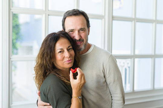 Middle age senior couple eating a fresh strawberry at home