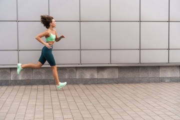 Fototapeta premium Sporty young woman athlete running on urban street in morning.