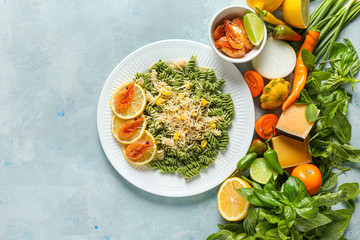 Plate with tasty pasta, shrimps and products on color background