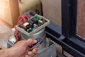 Technician man hand pressing remote control while repair and using digital clamp meter to test the...
