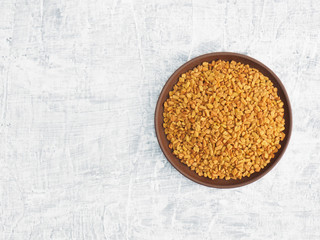 Spices and herbs help maintain good health and improve appetite, top view on white concrete background. Fenugreek in clay plate. Modern apothecary, naturopathy and ayurveda concept.