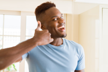 Handsome african young man doing thumbs up gesture, great symbol for succes smiling excited