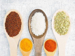 Spices and herbs set on concrete background in wooden spoon. Turmeric, fennel, mustard, chili pepper, masala. Modern apothecary, naturopathy and ayurveda concept.