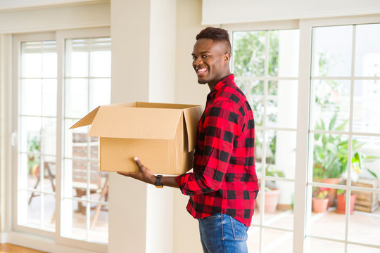 Young african american man holding a carton box, packing cardboard delivery package at home