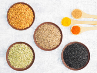 Spices set on concrete background in clay plate and spoon. Black cumin, jeera, fennel, fenugreek,...