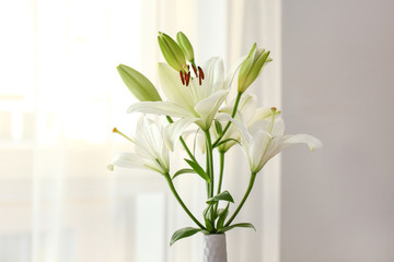 Beautiful lily flowers in vase in room