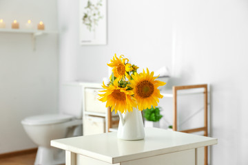 Beautiful sunflower flowers on table in bathroom