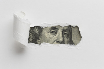 Ripped paper revealing dollar bill