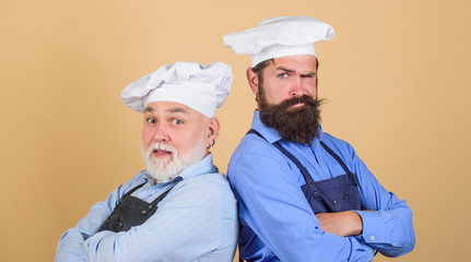 Nice taste. serious men in cook hat. mature bearded chef. tired of cooking. masters of kitchen. who is the best. father and son cooking together. commercial kitchen at restaurant. professional chefs