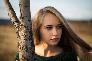 Autumn atmospheric portrait of an attractive girl with long hair in a green jacket.