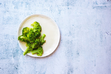 Cooked or steamed broccoli inflorescence, sprouts on plate.