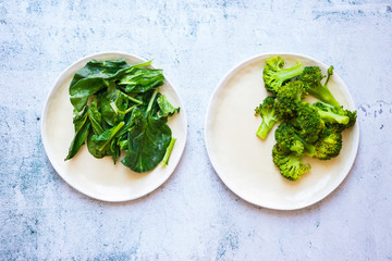 Fresh green spinach leaves and broccoli on plate.