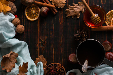 Iron mug with black coffee, honey, spices, on a background of a scarf, dry leaves on a wooden table. Autumn mood, a warming drink. Copy space.