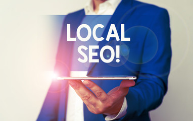 Handwriting text Local Seo. Conceptual photo incredibly effective way to market your near business online Man in the blue suite and white shirt holds mobile phone in the hand