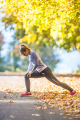 Female sporty young woman doing stretching or warming the body and preparing to jogging