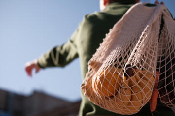 girl holds a rope bag with vegetables in her hands