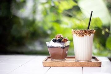 Closeup white chocolate milk with  chocolate mousse cake put on white desk with blur nature background. Snack and beverage in coffee cafe.
