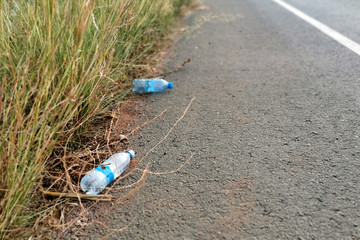 Plastic bottle on the floor beside the main road with copy space on the right side. Concept for...