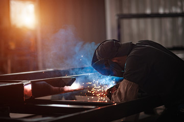 Work of the welder with metal. Sparks fly around the worker