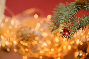Obraz na płótnie Canvas Christmas Golden toy bell on a spruce branch on the background of a Christmas garland . template for postcards . space for text