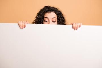Photo of funny lady not showing full face holding fingers big white placard presenting novelty information looking wondered isolated beige pastel color background - obrazy, fototapety, plakaty