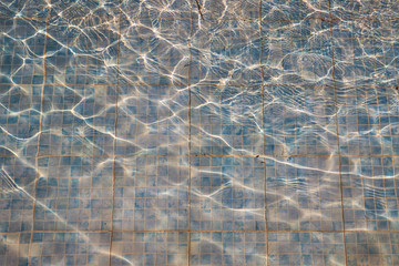 Old faded tiles in a dirty pool as a background.