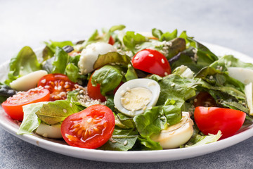 Fresh salad with tomatoes and quail eggs and lettuce.