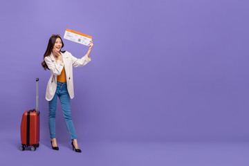 Full body of Attractive young Asian woman tourist with luggage showing confirmed boarding pass in transporting concept on banner size