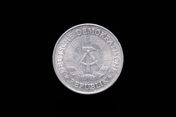 Old German Democratic Republic 1 Mark coin from 1977, obverse showing the national emblem of the GDR. Isolated on black background