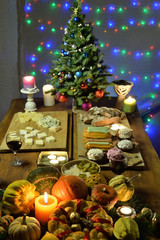 Christmas table with festive food, burning candles and a fir tree decorated