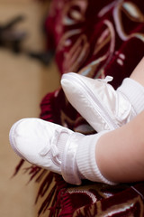 Fototapeta na wymiar White booties on the legs of a newborn