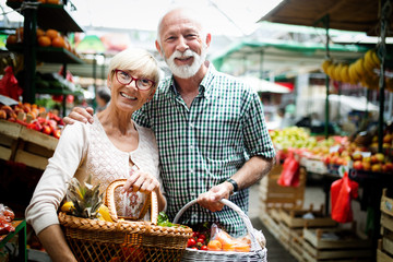 Mature shopping couple with basket on the market. Healthy diet.