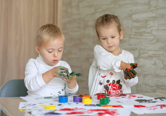 Little children paint with paints. The kids got their hands dirty in gouache. A cute girl and a boy...