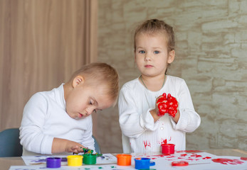 Little children paint with paints. The kids got their hands dirty in gouache. A cute girl and a boy...
