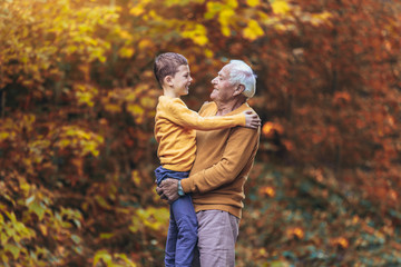 Grandfather and grandson together in autumn park