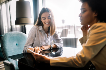 Successful attractive women friends chatting in cafe during coffee break