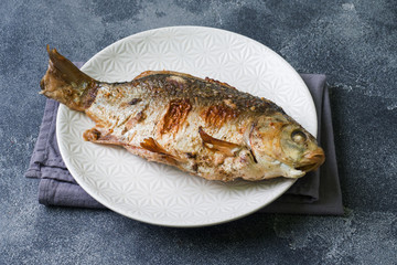 Baked carp fish on a plate. dark background. Copy space.