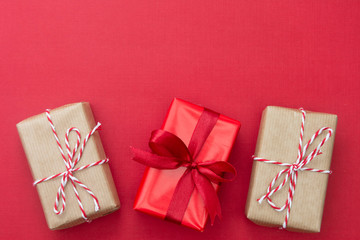 Christmas red background, mock up with craft paper gift boxes and copy space. Winter holidays with presents, top view, flat lay.