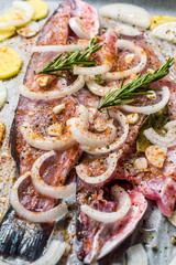 Raw Sea Bass Fish Fillet with Onions, Potatoes and Rosemary in Baking Tray with Paper at Oven Ready to Cook.