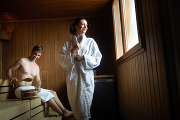 Obraz premium Beautiful young couple sitting together in a sauna