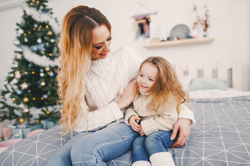 mother and daughter playing on the bed in a room decorated for the holidays