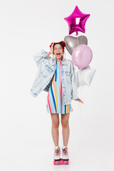Image of amazed young woman laughing and holding balloons