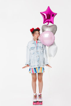 Image of amusing young woman grimacing and holding balloons