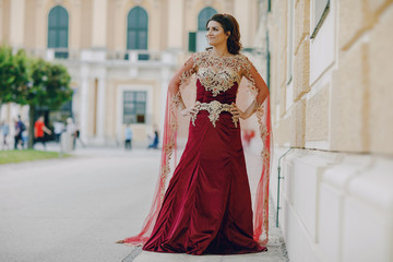 Obraz premium A beautiful Turkish girl in a long red dress walks in the summer old city