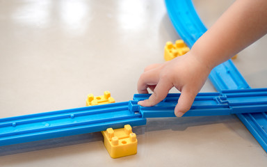 Close up of a little child's hands playing, assembling the colorful plastic railway track. Educational hands-on toys, Kids Thinking skills, Brain development. Japanese, JR, Popular Model train.