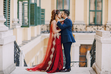 Beautiful woman in a long red dress walks around the city with her husband in a blue suit and with...